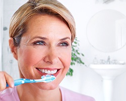 a dental implant patient brushing her teeth