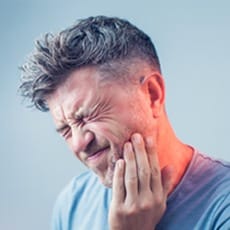 Man holding his jaw and wincing in pain