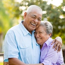 Smiling older man and woman hugging outdoors