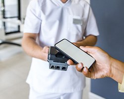 A woman using her smart phone to pay for dental care