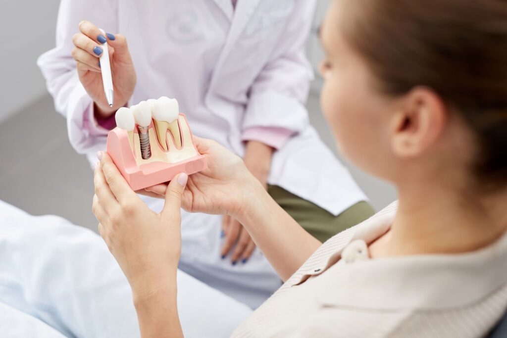 A woman looking at a model of dental implants in a jaw.